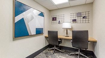 a room with a desk and two chairs and a lamp